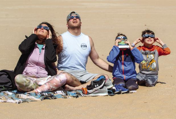 The McGeathe family enjoy the solar eclipse from the Dune Climb within the Sleeping Bear Dunes National Lakeshore on Monday, April 8. The eclipse occasion brought hundreds of people to the Dune Climb to enjoy the once-in-a-lifetime event. From left to right: Tracy, Dave, Lance, Hunter. Enterprise photo by Brian Freiberger