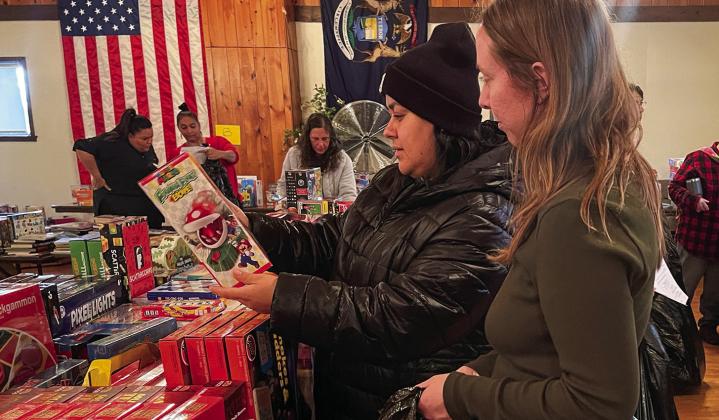 Volunteer Courtney Yaple, right, helps a shopper at the Holiday Needs Program distribution Tuesday at the VFW in Lake Leelanau. Onehundred, fifty-six families — more than 450 people — will have a wonderful Christmas because of the generosity of the community. Enterprise photo by Meakalia Previch-Liu