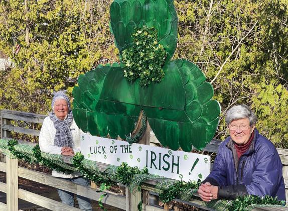 Judy Walter (left) and her husband, Jon, have been decorating the bridge off Elm Street in Suttons Bay since last July. Their latest creation, a giant green shamrock for St. Patrick’s Day, is on display for those passing by to see. Enterprise photo by Meakalia Previch-Liu