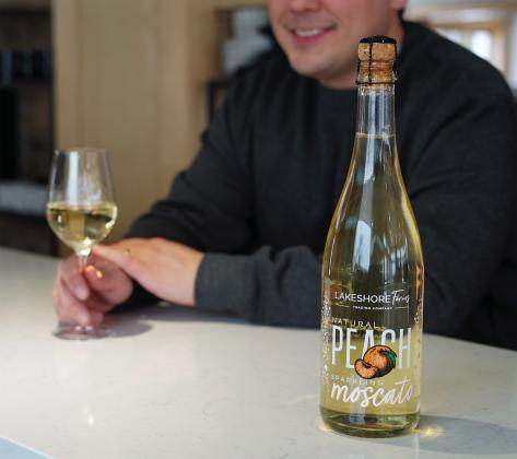 A customer is pictured enjoying Lakeshore Farms Peach Sparkling Moscato at Leelanau Cellars in Omena. Leelanau Cellars’ peach sparkling moscato won best of class in the fruit sparkling category this year at the San Francisco Chronicle Wine Competition, with the Leelanau Cellars team winning a total of 12 awards. Photo courtesy of Matthew Doyle