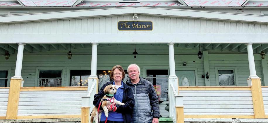 Owners Sue and Rob Rife are seen in front of Glen Lake Manor with their adopted dog, Jake. The former owner of The Manor, Nancy Wright, passed away in 2020, and her sister, Sue, took in her beloved dog, Jake, soon after. Enterprise photo by Meakalia Previch-Liu