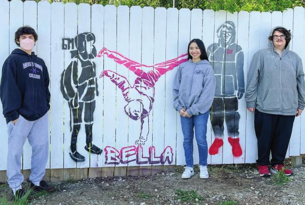 From left to right, Northport Public School seniors Gavino Martinelli, Isabella Rice, and Davis Fredrickson stand next to some freshly spray painted life-size portraits along the fence at Around the Corner in Northport. Photo courtesy of Jenny Evans