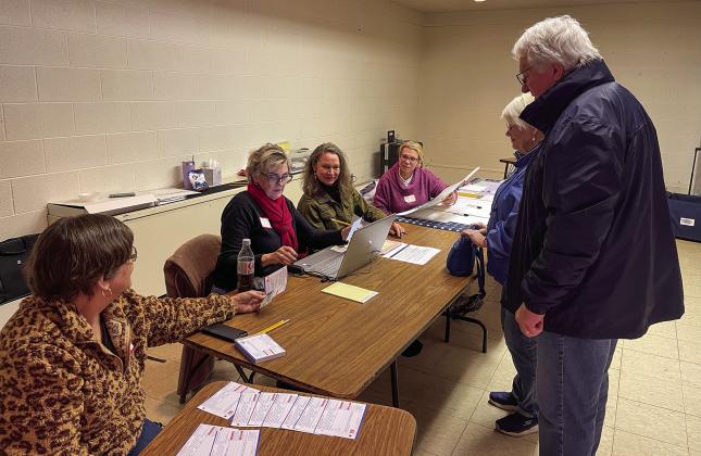 Election workers stationed at Suttons Bay Public School are pictured helping people check in before they get their ballots on Tuesday evening. Enterprise photo by Meakalia Previch-Liu