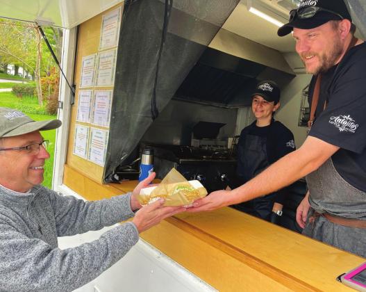 Josh Rutila hands a customer his order. Rutila and his wife Elizabeth operate and own the Mexican taco truck called Antojitos: Little Cravings in Northport. Enterprise photo by Meakalia Previch-Liu