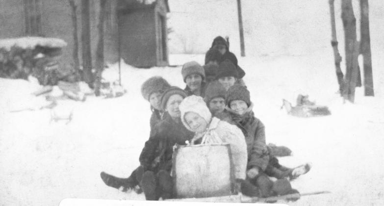 Laura Basch: “One of the things we had—I don’t know who furnished the toboggan, but somebody furnished a toboggan; and I have a picture of it, and I’ll find it, too, for you. It’s a picture of a whole bunch of us kids on the toboggan and that little hill as you go down to the lake. We could go one place there and sled down. We was not allowed to go on the lake (which had a reputation for being dangerous.) We’d just go so far on that toboggan.” C. 1921 Courtesy photo
