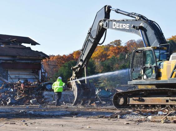 A demolition worker from Kalamazoo-based Taplin Enterprises sprays water to keep the dust down as demolition of the main lodge building at Sugar Loaf Resort continues this week. Enterprise photo by Eric Carlson