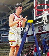 Ferris State redshirt junior Reece Hazelton cuts down the net after winning a regional championship in the NCAA DII men’s basketball championships. Courtesy photo